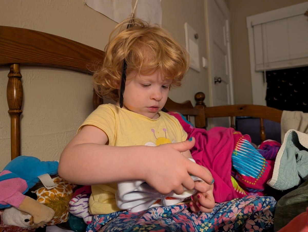 A young child sitting on a bed, absorbed in play