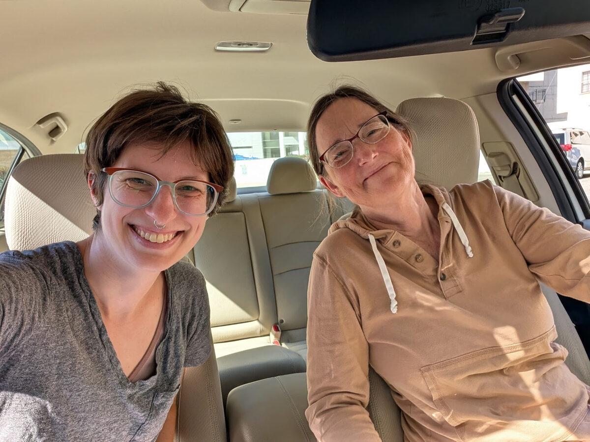 Pastor Remi and a friend smiling in the front seats of a car