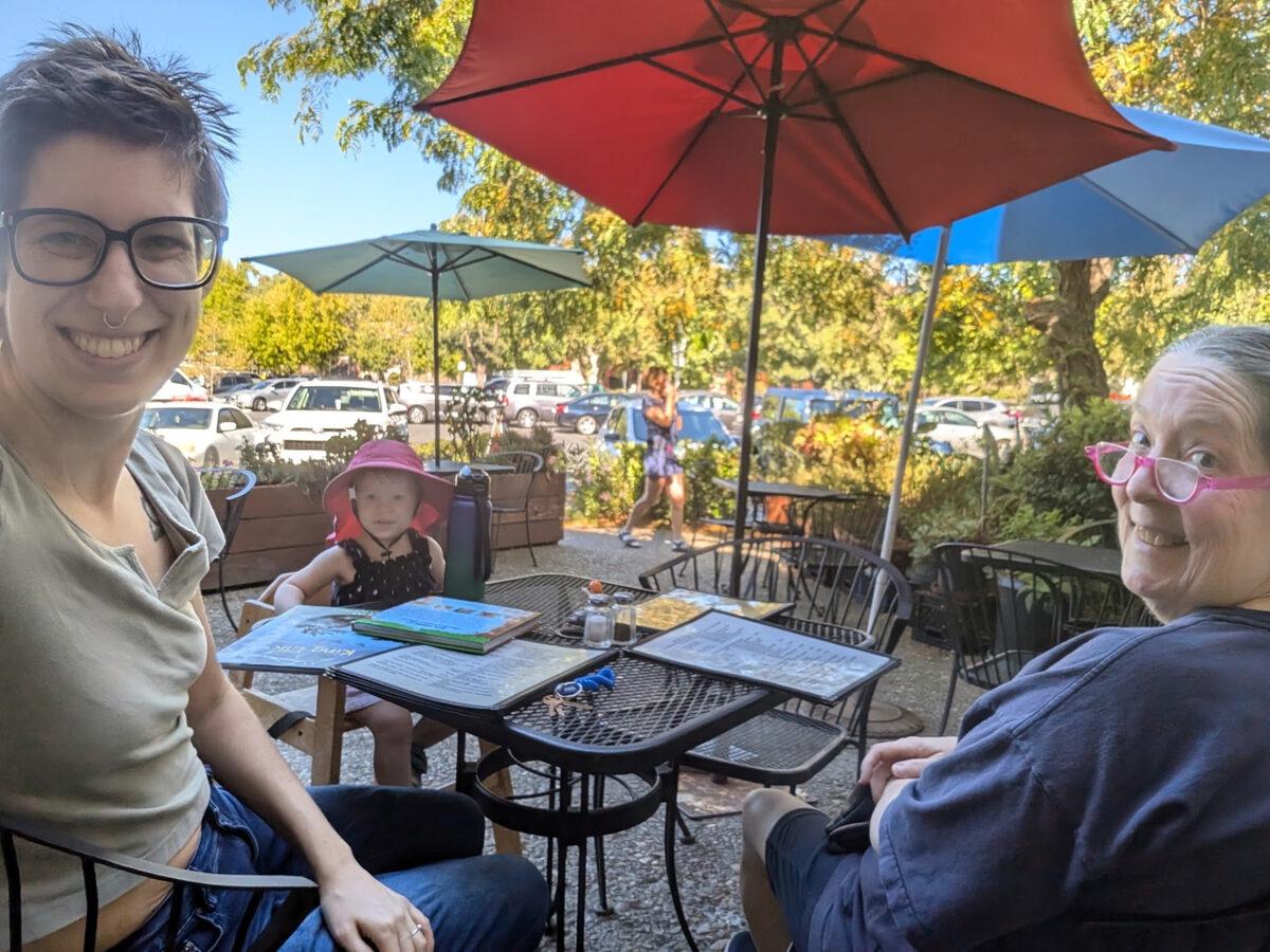 Pastor Remi sharing a patio table with friends under red umbrellas