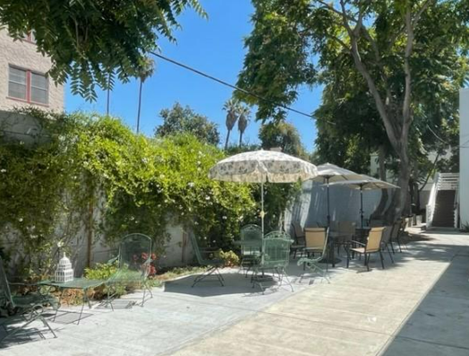 Cement floors with tables, chairs and umbrellas, outside.